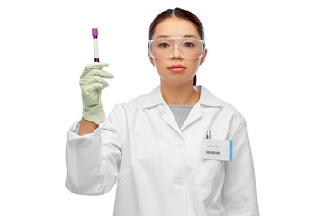 medicine, health and pandemic concept - young asian female doctor or scientist in goggles holding beaker with blood test