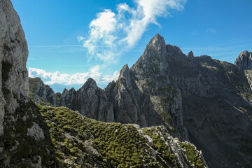 A panoramic view on Alpine slopes in Austria. There are sharp ans steep mountains and high peaks around. The Alpine slopes are almost barren, just moss overgrowing the slopes. Serenity and freedom.