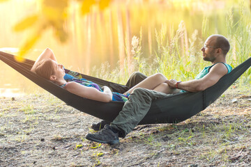 portrait camping and resting man and woman lying in hammock in green forest