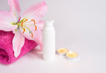 Spa salon, cosmetics in a white bottle, towel, candle, lily flower and palm leaves on a white background. Healthy lifestyle. copy space