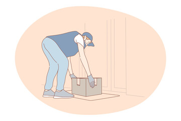 Contactless delivery, courier, online order concept. Young man courier deliveryman in protective medical mask and gloves putting parcel on floor near customer door. Parcel, logistics during pandemic