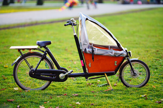 Schönes Kinder Cargo-Rad mit Schutz-Zelt Parkmöglichkeiten auf dem Rasen, Lastenfahrrad, Familienrad