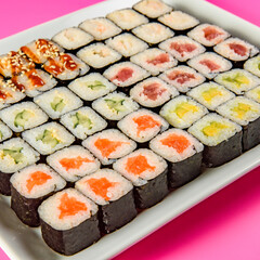 Mix of Japanese maki nori rolls in on a pink background