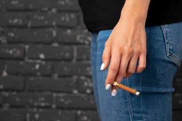 Female hand holding lighted cigarette close up