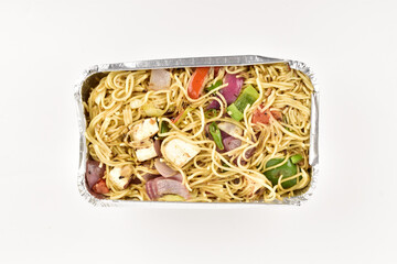 Top view of veg Hakka noodles on foil tray on white background