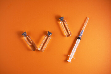 Medical bottle, vials, syringe on an orange background. Vaccination and development of immunity....
