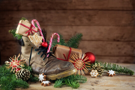 German tradition to put the shoes in front of the door on Nicholas or Nikolaus day at 6th December to get them filled with treats, old hiking boot against a rustic wooden background, copy space