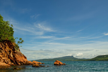 Naklejka premium seascape scenic red cliff island with cloudy sky