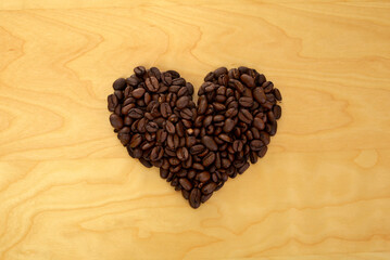 Heart shaped roasted coffee beans on wooden background