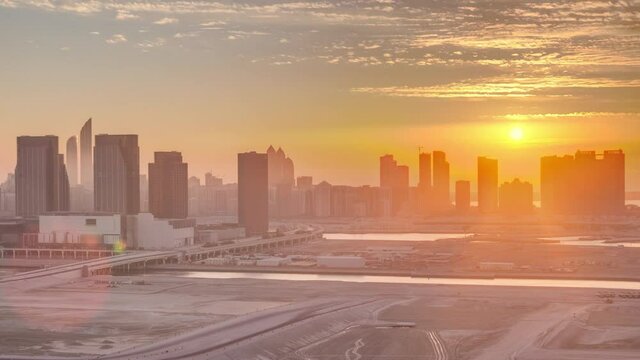 Skyscrapers on Al Reem and Al Maryah Island in Abu Dhabi at sunset timelapse from above. Aerial citiscape from Al Reem Island with modern buildings. Orange sky
