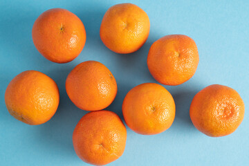 Scattered clementines, tangerines, mandarins, oranges on blue background. Winter vitamins