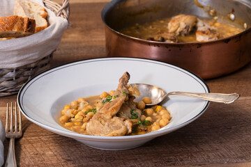 close up of a delicious looking plate of chickpea and meat stew with a spoon on a wooden table