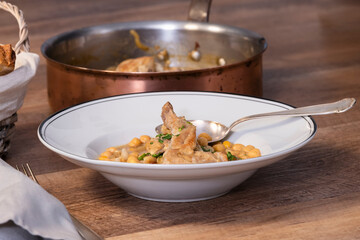 close up of a plate with chickpea and meat stew with an out of focus pan at the back