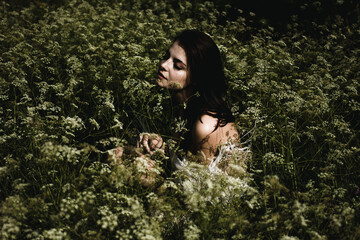 Young woman with black hair and naked back among wildflowers