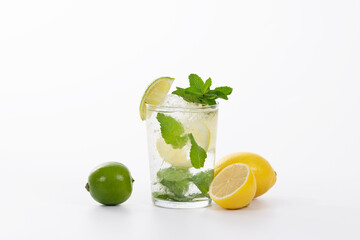 Fototapeta premium view of a tempting glass of mojito cocktail with fresh lemons and a lime on a light background
