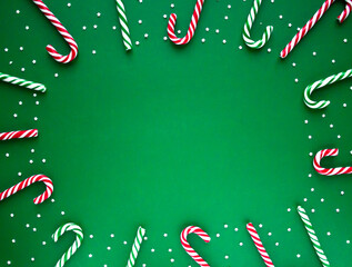 Christmas background with candy canes. Frame made of red and green sweet sticks with small stars. Flat lay, overhead view. Poster, banner, greeting card template. Festive backdrop. Holiday season
