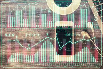 Double exposure of forex chart hologram over desktop with phone. Top view. Mobile trade platform concept.