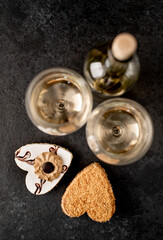 Festive dinner for two for valentine's day. Heart shaped cakes and white wine bottle with glasses on stone background