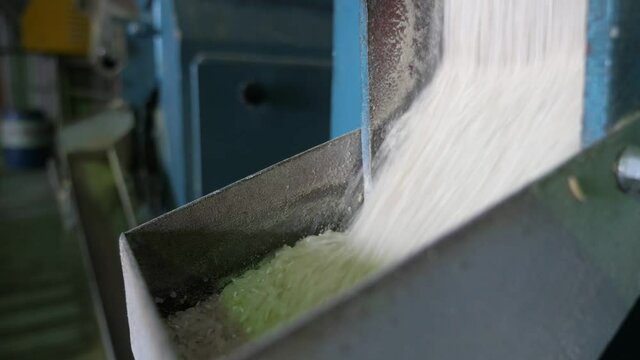 Rice sifting through a large metallic gutter at a contemporary agricultural plant