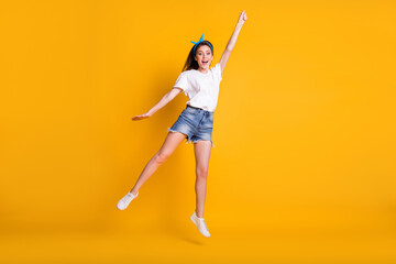 Fototapeta na wymiar Full length body size photo of playful girl jumping up like superhero superwoman on vibrant yellow color background