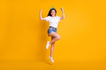 Fototapeta na wymiar Full length body size photo of girl demonstrating strong hands muscles biceps jumping high on vivid yellow color background