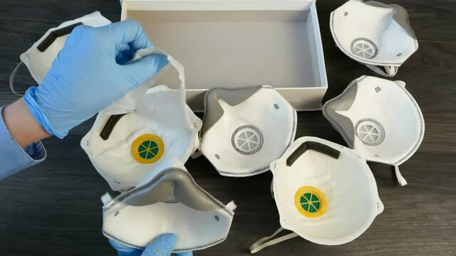 Hand in medical gloves packing many different respirators with high protection level 3M, ffp2 and ffp3 N95. Protection against coronavirus. Respritors production, packing and delivery