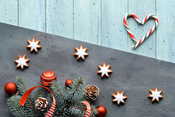 Zero Waste Christmas background. Xmas flat lay with heart from stripy candy canes. Fir twigs, ribbons, cones, star cookies and red balls. Dark light split wooden background. Happy New Year