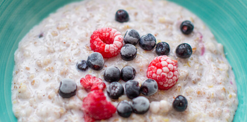 Oatmeal porridge in a plate with currant and raspberry berries. 
