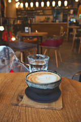Cozy remote working morning in cafe - cup of delicious cappuccino coffee, protection mask, laptop on desk and books
