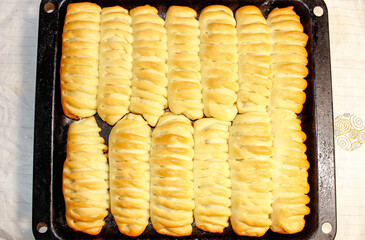 Rosy homemade rolls on a baking sheet baked in the oven. Homemade cake.