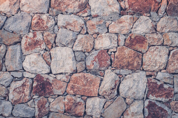 Modern wall of large unprocessed pieces of rock, stones. Background stone wall.