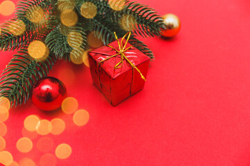 Christmas composition. Gift, fir tree branches, decorations on red background. Christmas, winter, new year concept. Flat lay, top view, copy space.