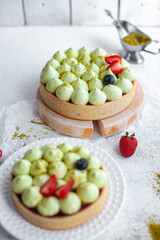 Round shortcrust cake with green pistachio cream and strawberry jam. Pistachio tart with cream cheese