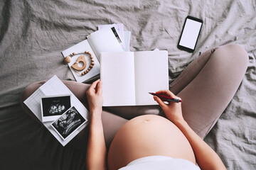 Pregnant woman with notebook, ultrasound image and prenatal documentation. Expectant mother during...