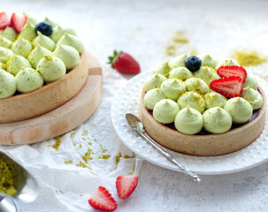 Two Round shortbread pies with green pistachio cream and strawberry jam, close-up. Pistachio tart with cream cheese