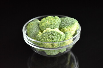 Green organic not cooked broccoli, close-up, over black background.