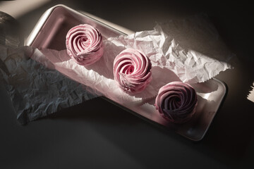 Pink strawberry homemade zephyr or marshmallow in a rectangular oleum plate in the sun on the table. Copy spase