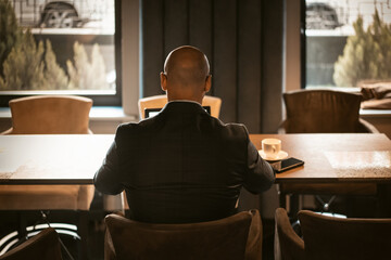 Back view of elegant CEO dressed in expensive suit sitting at the table in the modern expensive...