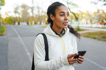 African american sportswoman using smartphone while walking in park