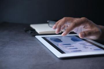 man's hand working on digital tablet at office desk, using self created chart 