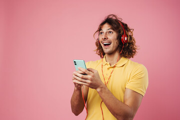 Excited handsome guy listening music with headphones and mobile phone