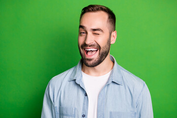 Obraz premium Portrait of optimistic man wear blue shirt blink open mouth isolated on green color background