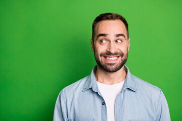 Portrait of optimistic funny man wear blue shirt look empty space isolated on green color background