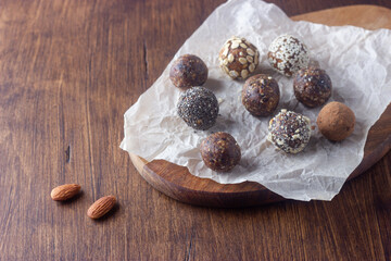 Raw vegan healthy energy balls with oatmeal, chia seed, coconut flakes, cocoa, almond and dried fruits on dark wooden background. No cook energy bites.