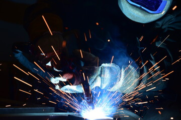 Employee welding steel with sparks using mig mag welder - focus on sparks.