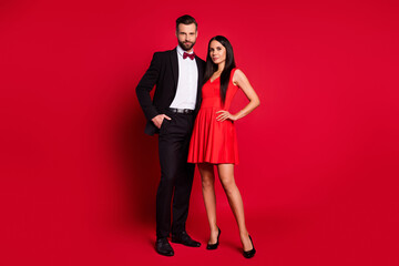 Full size photo of optimistic couple stand wear vivid dress black suit isolated on red color background © deagreez