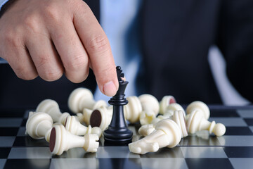 Businessman finger hands control chess king to success position on competition business game with...