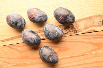Ripe dark purple plums, close-up, on a wooden table.