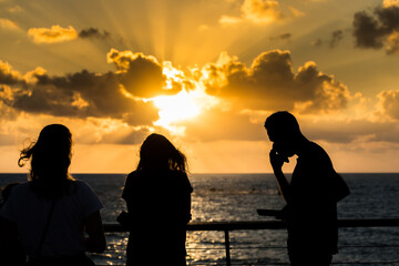 Beautiful sunset and golden twilight, and clouds, Silhouettes of people standing on the coast of Mediterranean sea in Israel and watching the sunset
