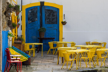 Colored, yellow, blue, green and red chairs in front of building. Beautiful coffee house and restaurant.